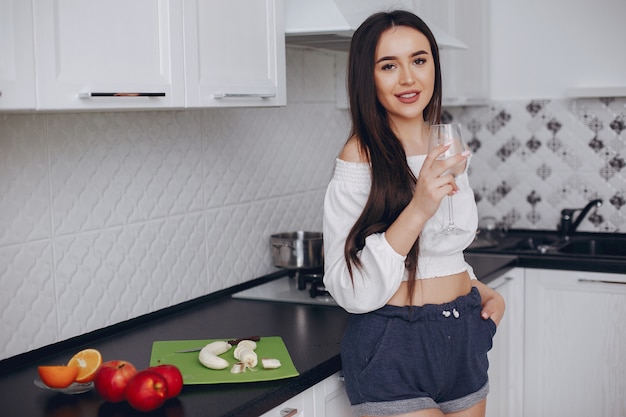 Menina elegante em uma cozinha com frutas