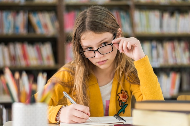 Menina, em, óculos, estudar, em, biblioteca