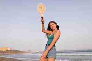 Foto grátis menina, em, topo biquíni, e, shorts, segurando, raquete, em, praia