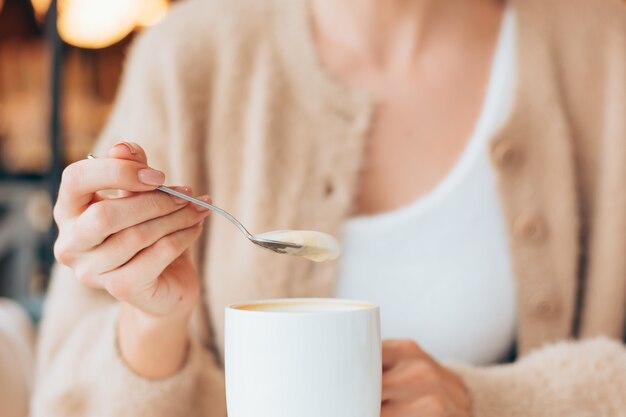 Menina em um café com uma xícara de café com leite quente