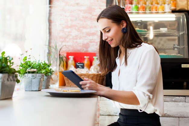 Menina em um café lê algo no tablet