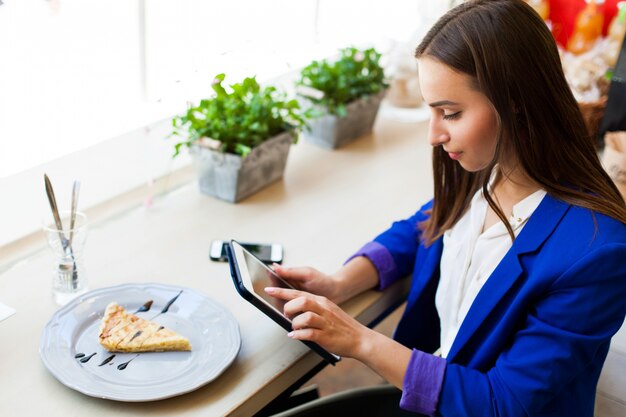 Menina em um café lê algo no tablet