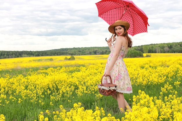 Menina em um campo de flores com um guarda-chuva e um chapéu Foto Premium
