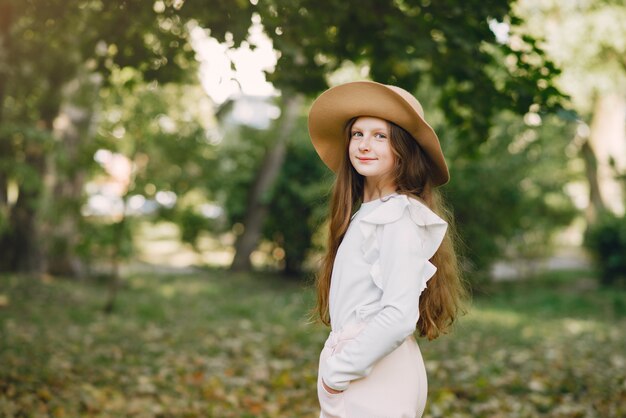Menina em um parque em pé em um parque com um chapéu marrom