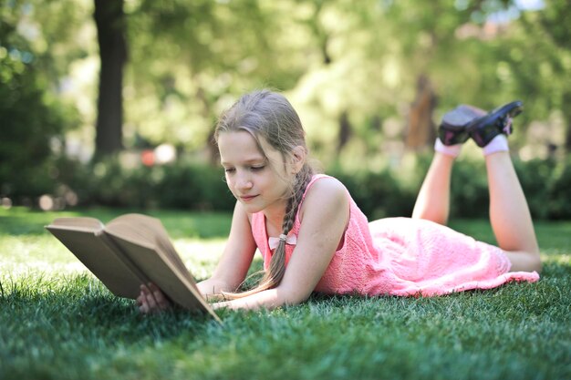 menina em um parque lê um livro