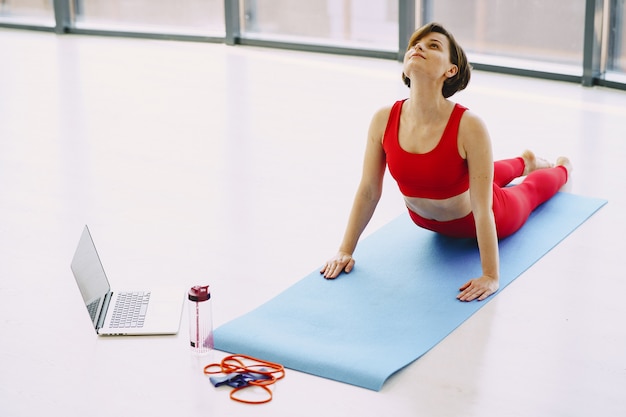 Foto grátis menina em um uniforme vermelho esportes praticando ioga em casa