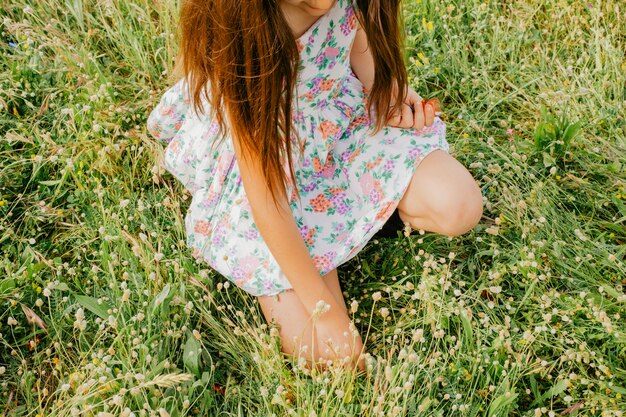 Menina em vestido floral sentado no campo