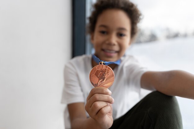 Menina embaçada de tiro médio segurando medalha