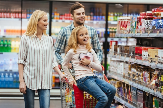 Menina encantada, sentado em um carrinho de compras