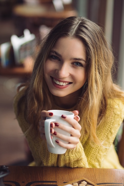 Menina encantadora, bebendo cappuccino e comendo cheesecake