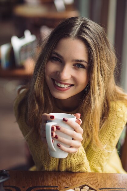 Menina encantadora, bebendo cappuccino e comendo cheesecake