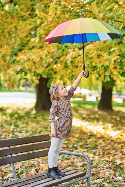 Menina encantadora com guarda-chuva colorido no parque outono