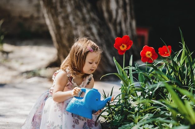 Menina encantadora cuida de flores no jardim