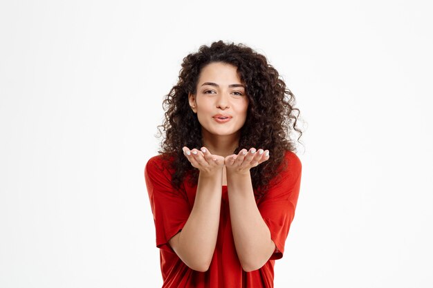 menina encaracolada alegre mandando beijo