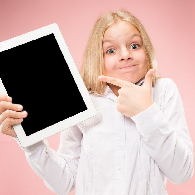 Menina engraçada com tablet em estúdio rosa