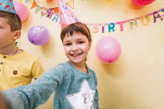 Menina engraçada tomando selfie na festa de aniversário