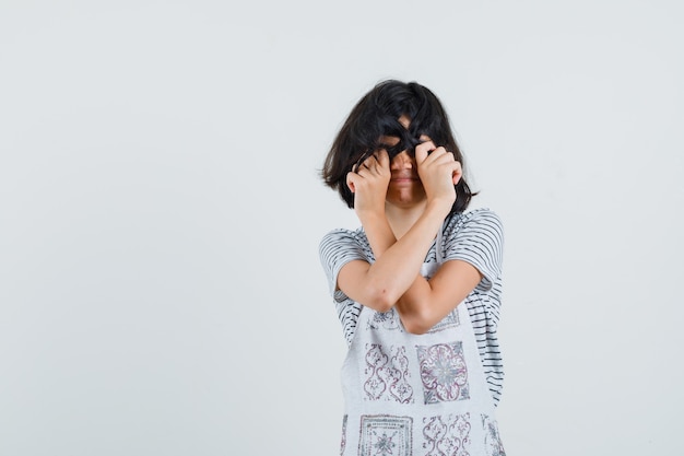 Menina escondendo os olhos atrás do cabelo em camiseta, avental,