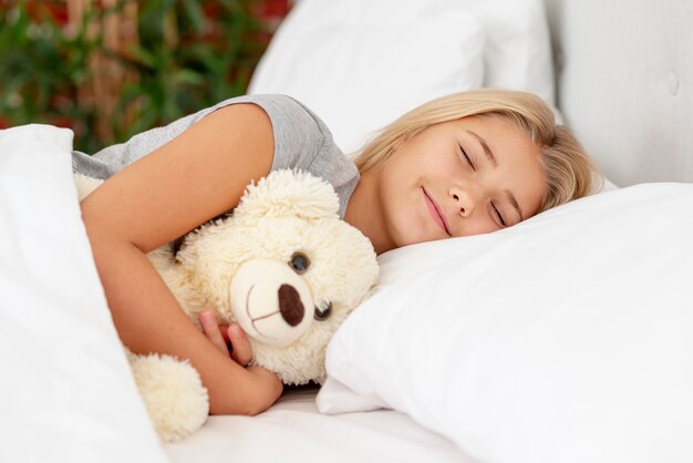 Menina escorregando com seu urso de brinquedo