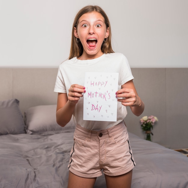 Foto grátis menina espantada, segurando o cartão com inscrição feliz dia das mães