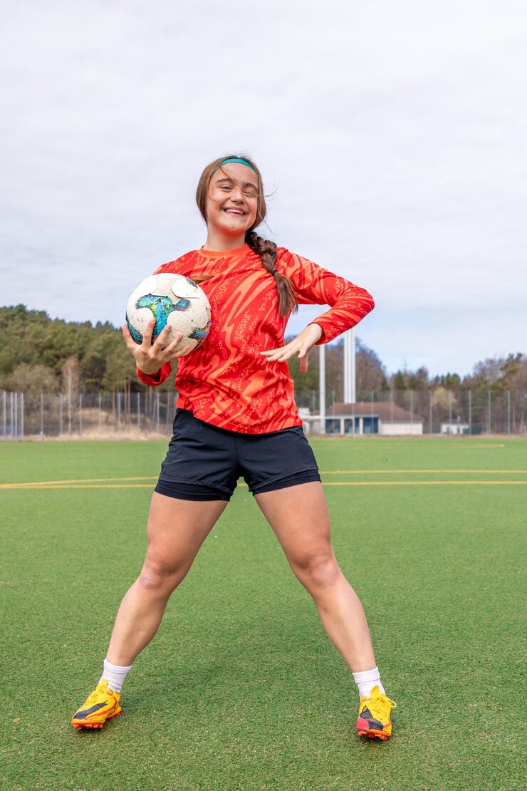 Foto grátis menina esportiva segurando uma bola de futebol em suas mãos menina jogadora de futeblol em treinamento de futebal