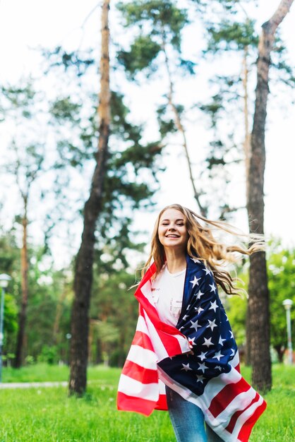 Menina feliz com a bandeira americana na natureza