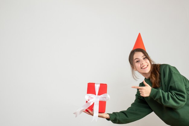 menina feliz com boné de festa apontando para um presente em branco