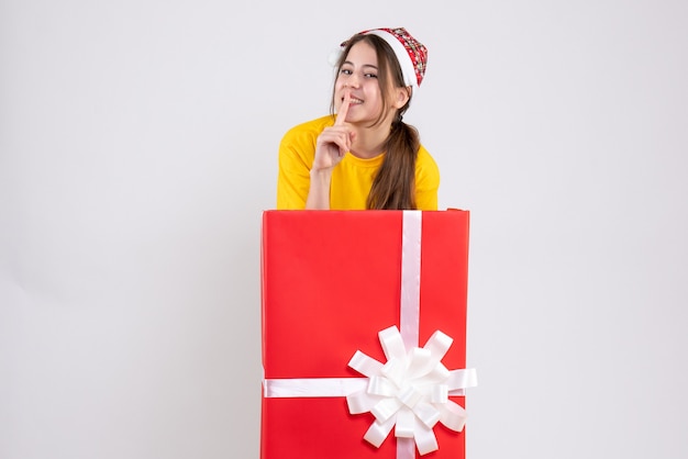 Menina feliz com chapéu de papai noel atrás de um grande presente de natal em branco