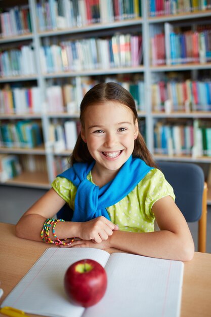 Menina feliz com uma maçã no caderno