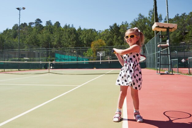 Menina feliz jogando tênis. Esporte de verão