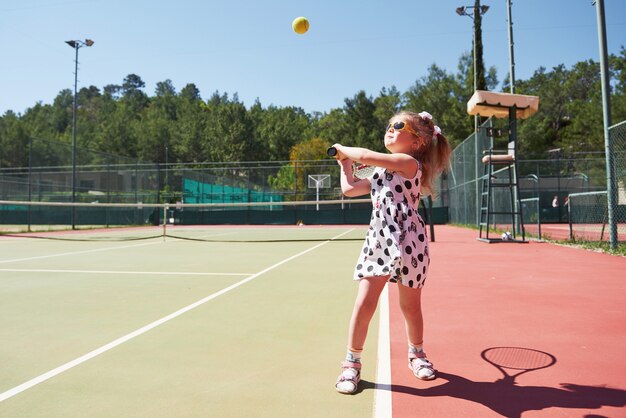 Menina feliz jogando tênis. Esporte de verão