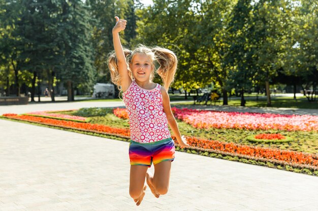 Menina feliz pulando no parque. menina tomando sorvete e se divertindo na cidade.