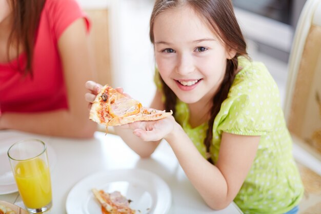 Menina feliz que come a pizza