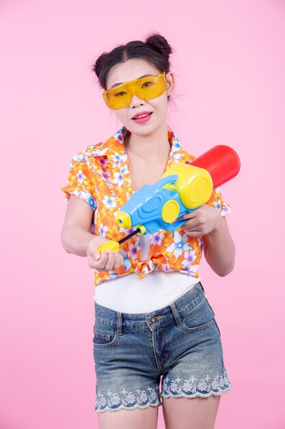 Foto grátis menina feliz que guarda uma arma de água cor-de-rosa do fundo.