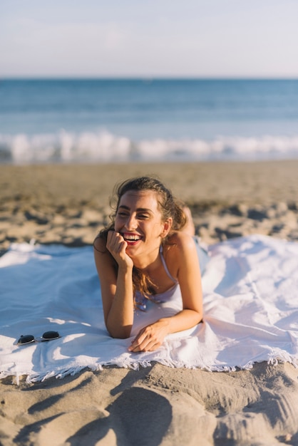 Menina feliz que toma banho de sol na praia