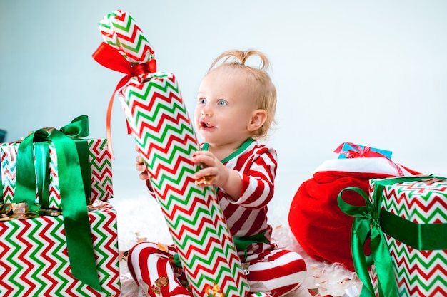 Menina fofa de 1 ano perto de chapéu de Papai Noel posando no Natal