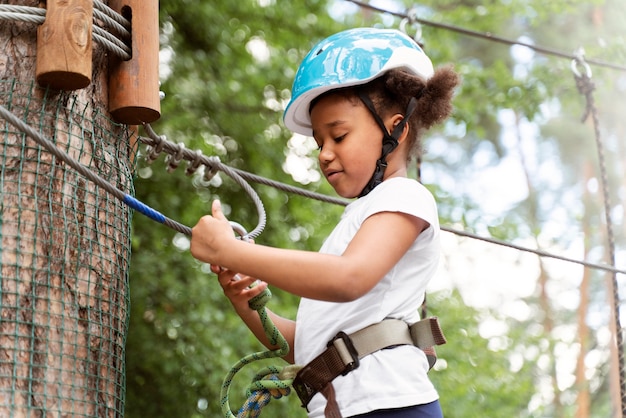 Menina fofa se divertindo em um parque de aventura