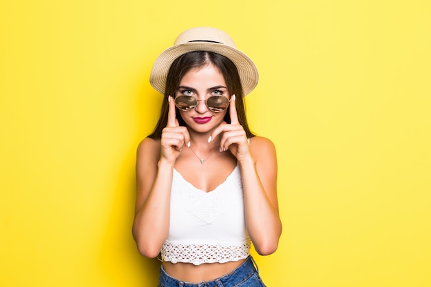 Menina hippie animado com chapéu e óculos de sol na parede amarela