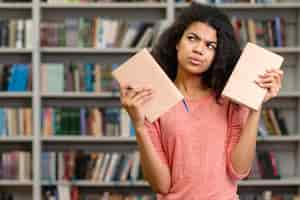 Foto grátis menina indecisa em escolher um livro para ler