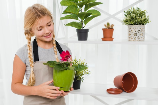 Menina jovem, segurando, pote flores