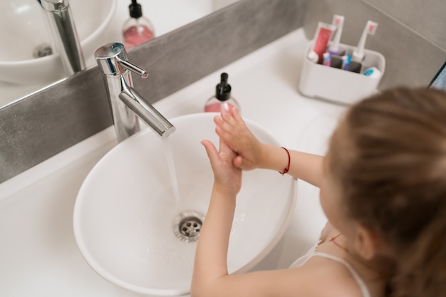 Menina lavando as mãos com sabão
