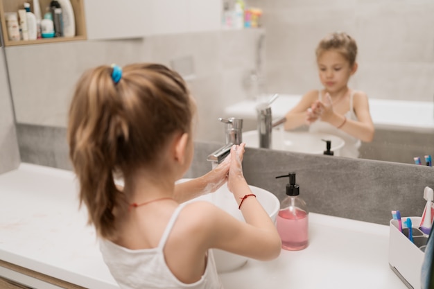 Menina lavando as mãos com sabão