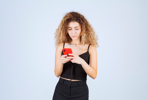 Menina lendo suas mensagens no smartphone e parece pensativa.