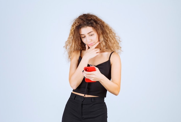 Menina lendo suas mensagens no smartphone e parece pensativa.