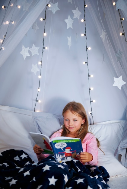 Foto grátis menina lendo um livro na cama