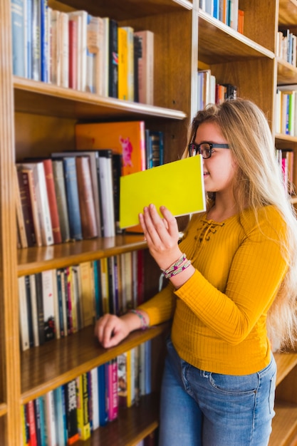 Menina, levando, livro, em, biblioteca escolar