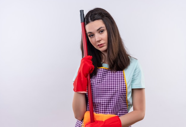 Menina linda com avental e luvas de borracha segurando o esfregão, parecendo cansada e sobrecarregada