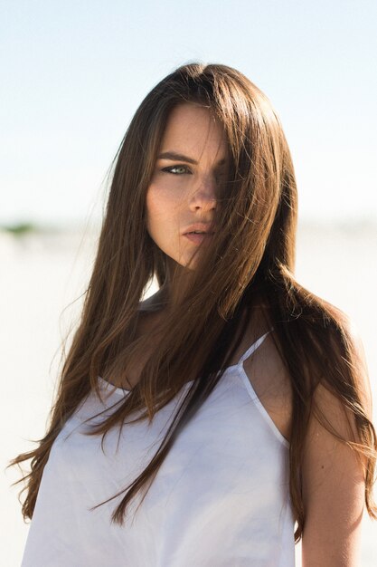 Menina linda com cabelo moreno longo e top branco