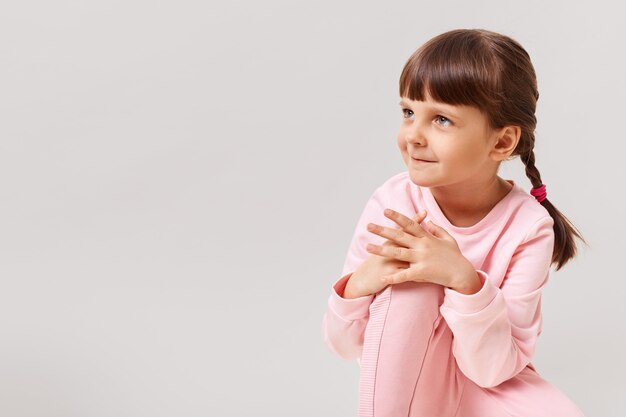 Menina linda e fofa olhando para o lado com interesse