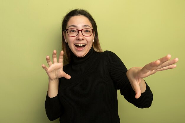 Menina linda em uma gola preta e óculos sorrindo de mãos dadas e confusa