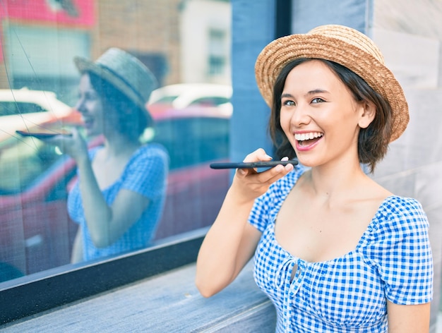 Foto grátis menina linda sorrindo feliz usando smartphone encostado na parede da rua da cidade